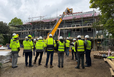 A group of professionals in PPE standing in front of a SIPs house construction project